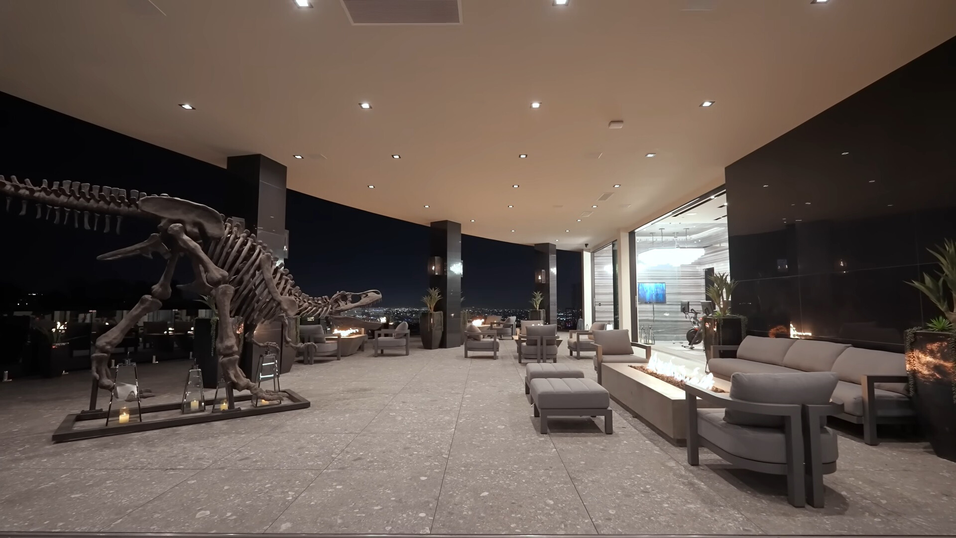 outside area of the house with couches, chairs, fire table and a dinosaur skeleton