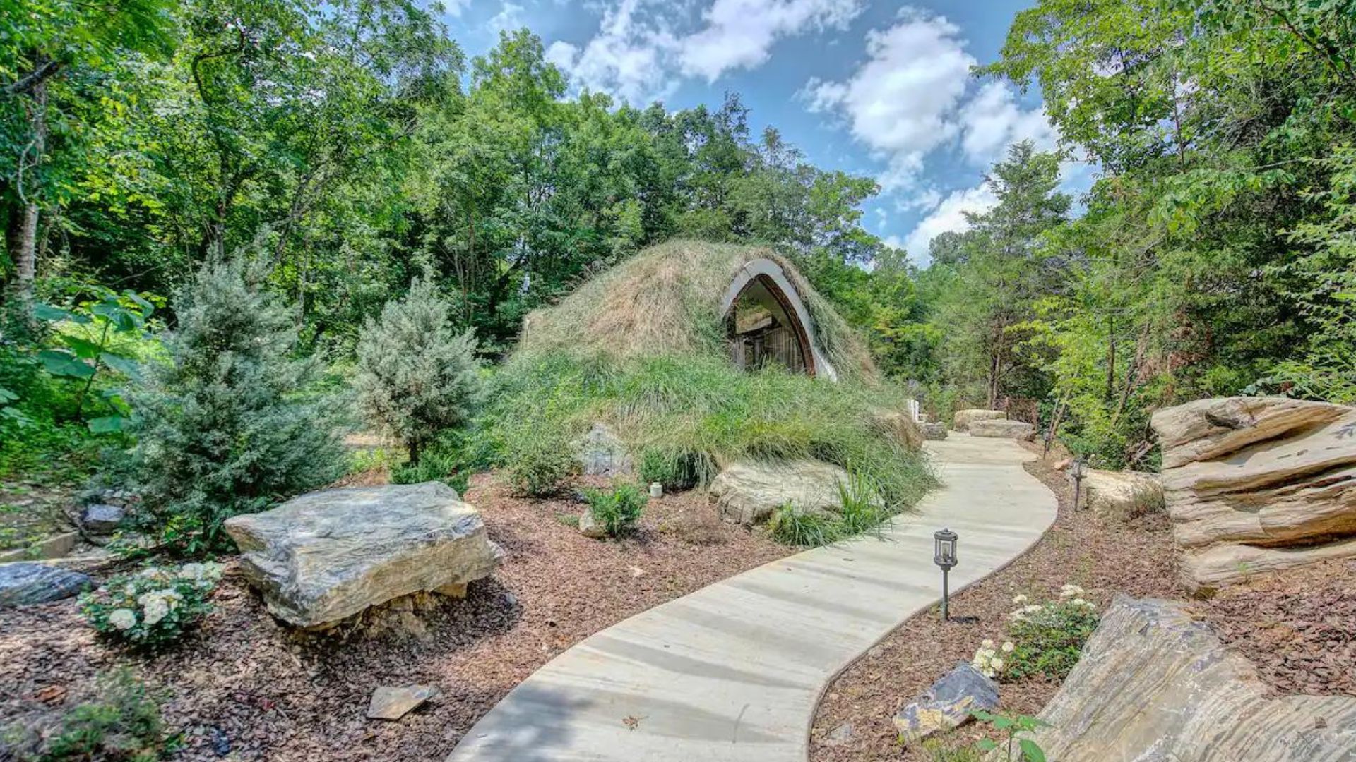 path leading to the small hobbit-like house under ground covered in grass, surrounded by the woods