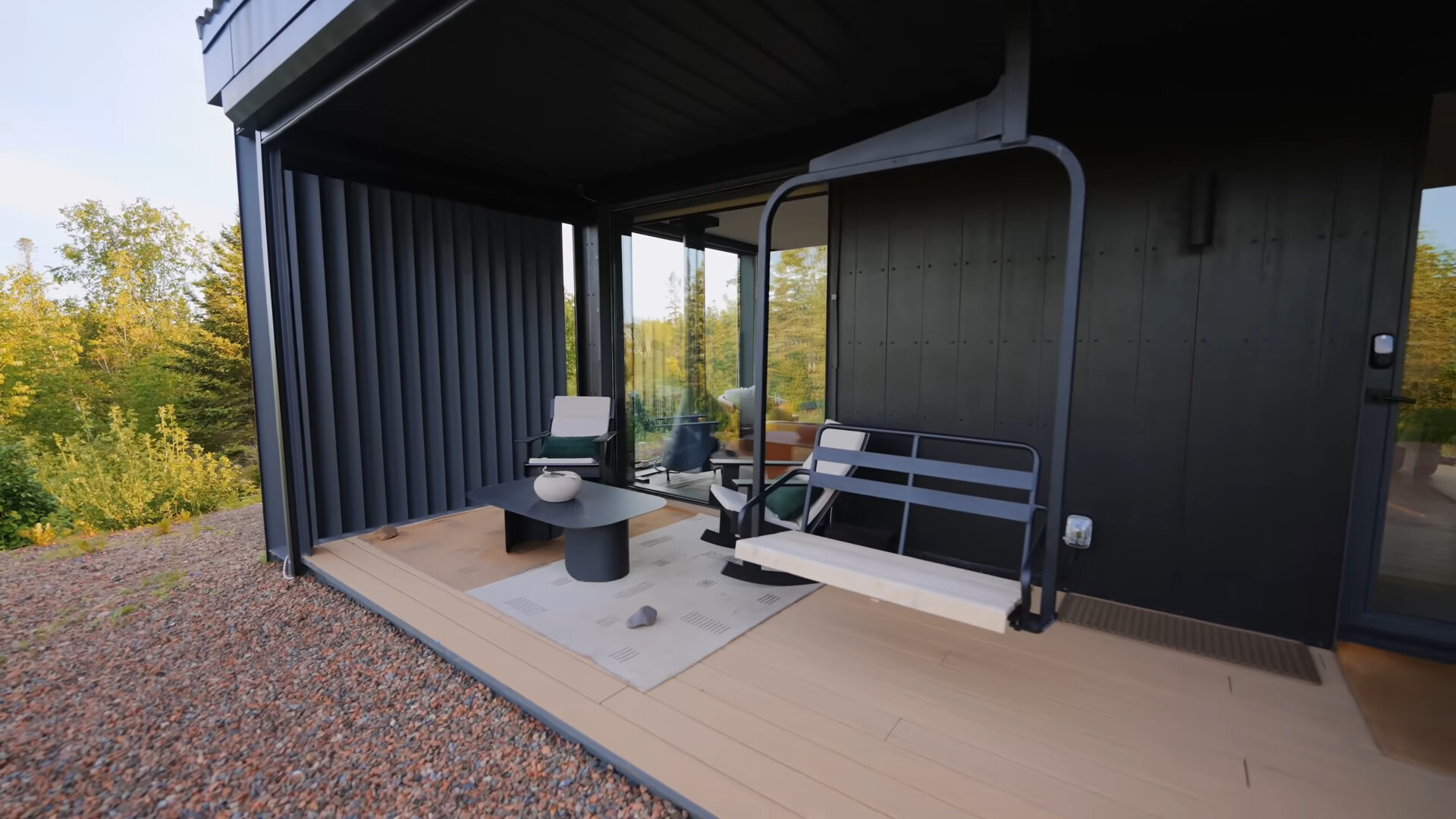 patio of a container house with a mini black table, two chairs and a ski lift hanging chair