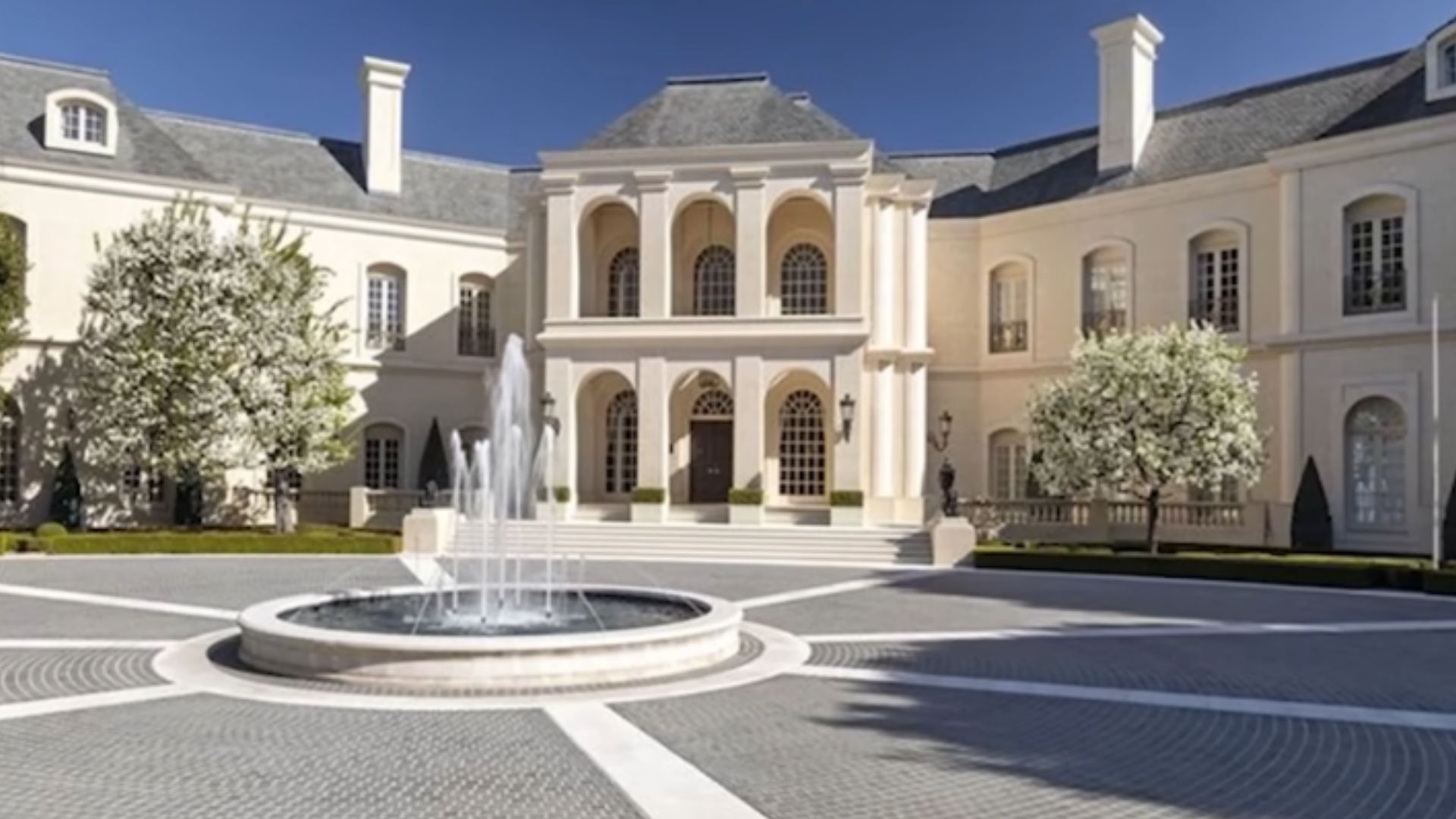 petra ecclestone mansion in los angeles with a round fountain at the front, big, white building with lots of windows