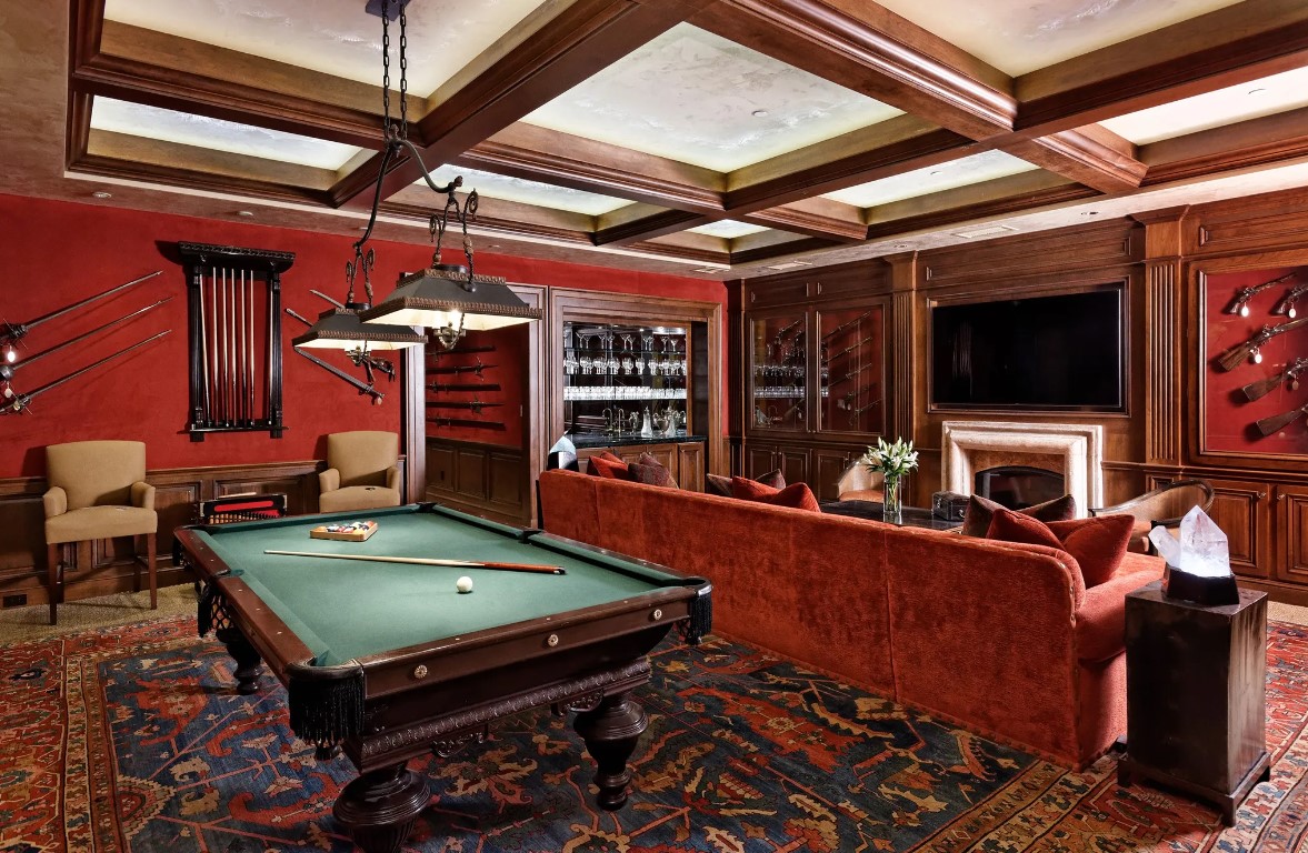 pool table in a room with red walls, red couch and flat screen tv