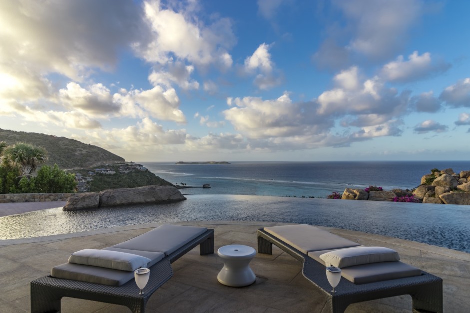 pool with deck chairs and an ocean view