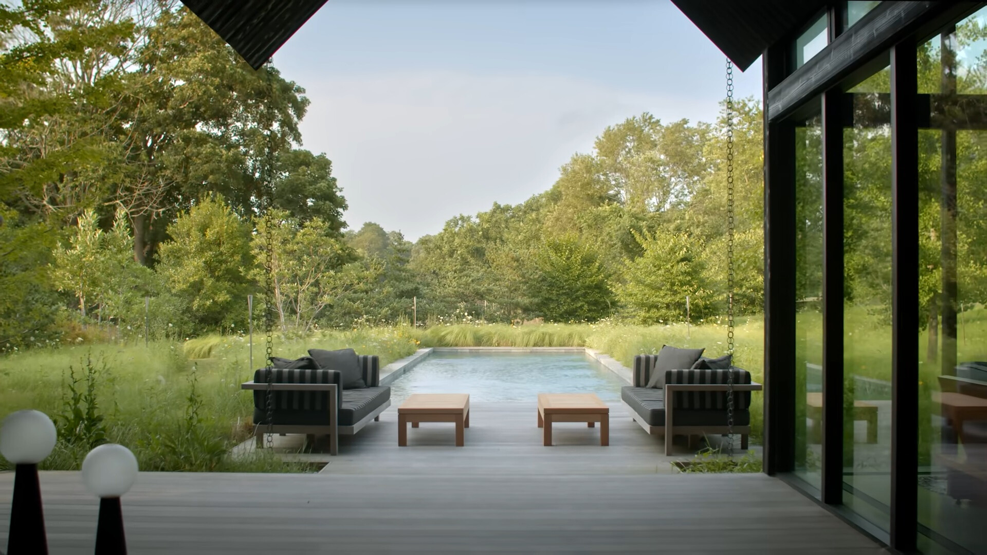 pool with furnished couches and a mini table surrounded by greenery