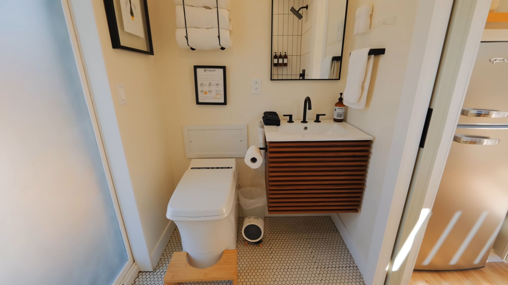 small bathroom in white with black hardware, a lovely wooden vanity that's floating, and an incinerating toilet