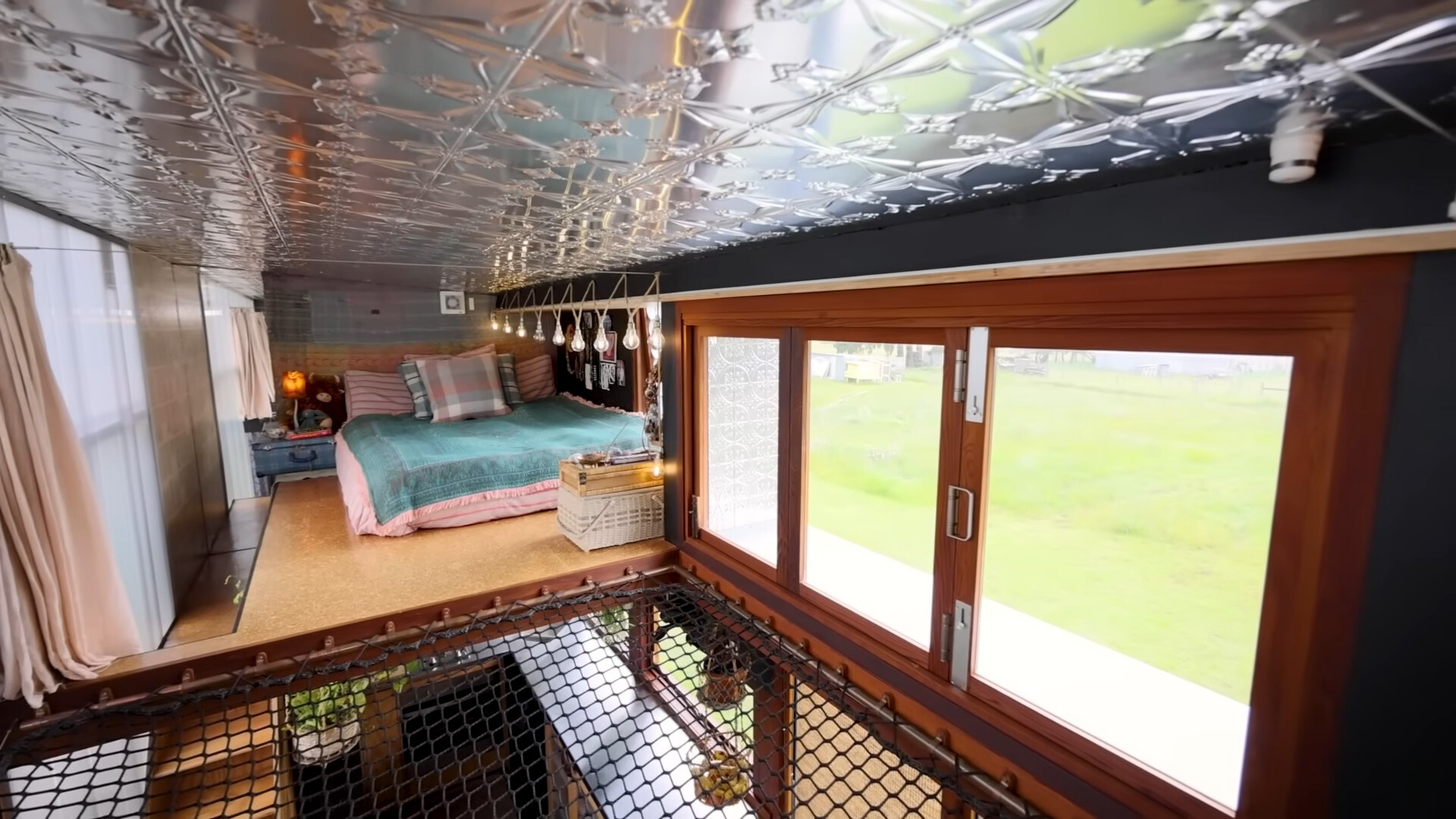 loft bedroom with blue bed sheets and a net connecting it with the other room