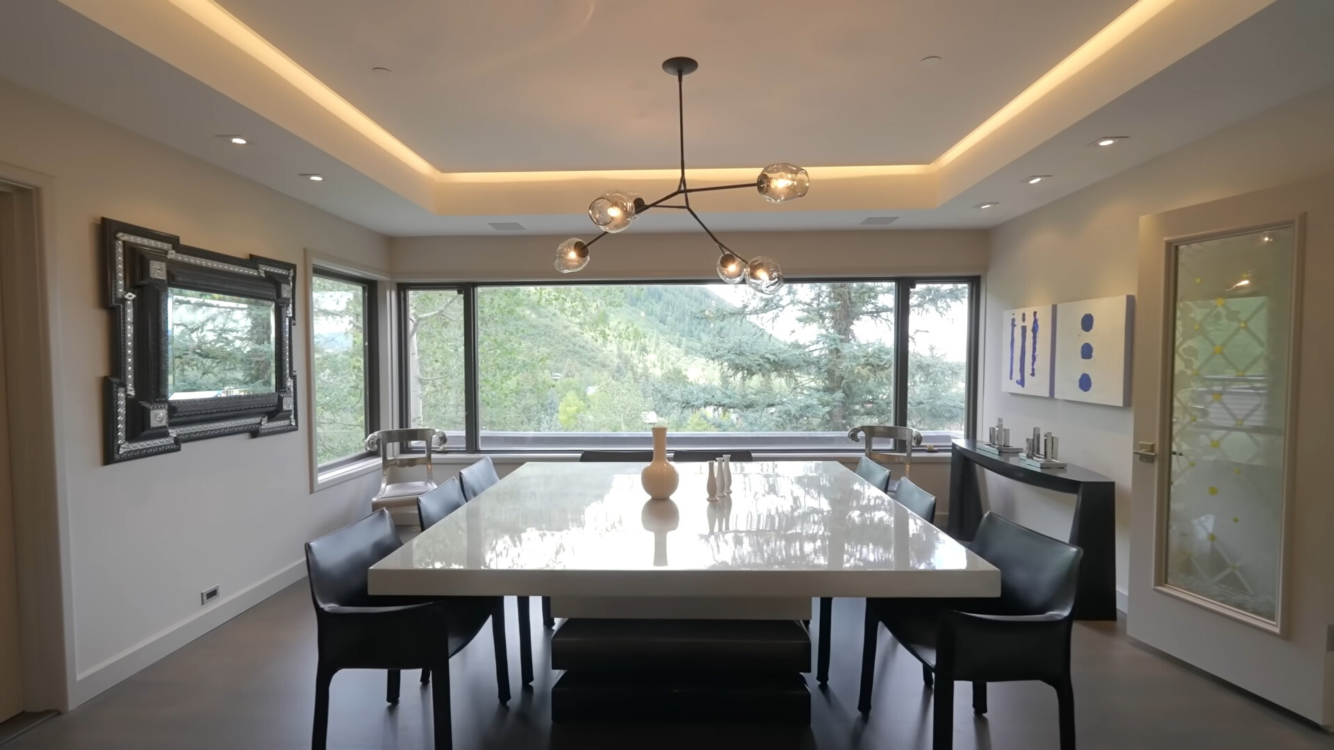 dining room with a white table surrounded by black chairs and big windows