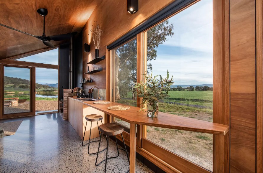 built in wooden dining table with two chairs next to a huge window