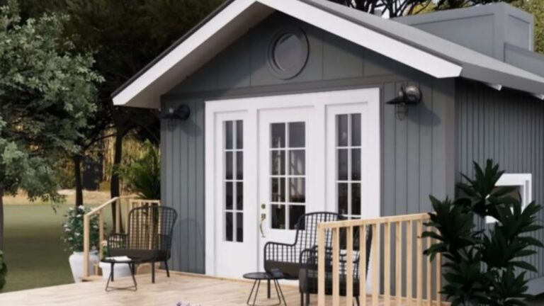 tiny house with grey exterior and wood siding, front porch with two seating areas, lots of plants and greenery, white french door and windows