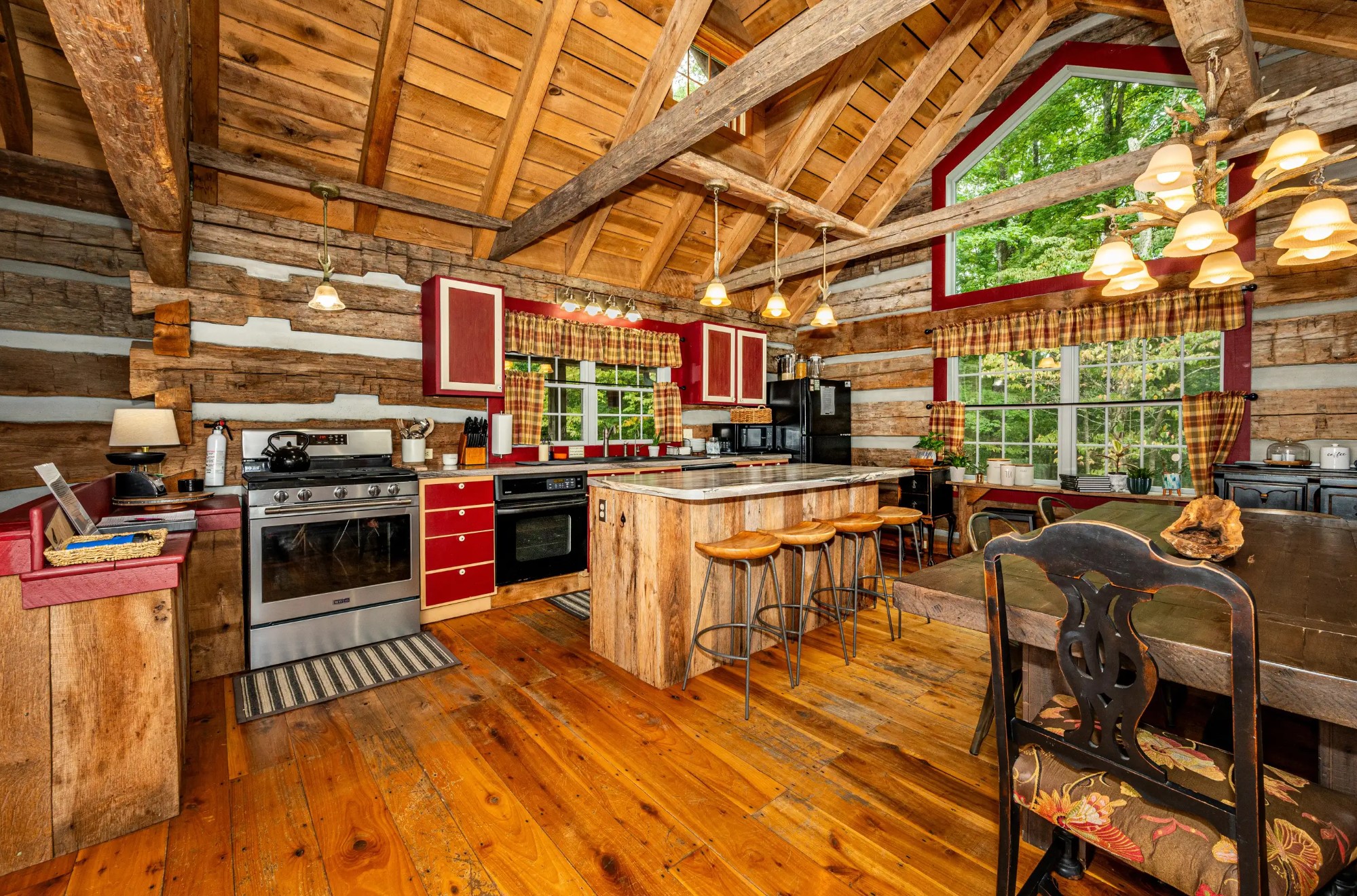 Cabin kitchen with red cabinets, wooden floor, and an island