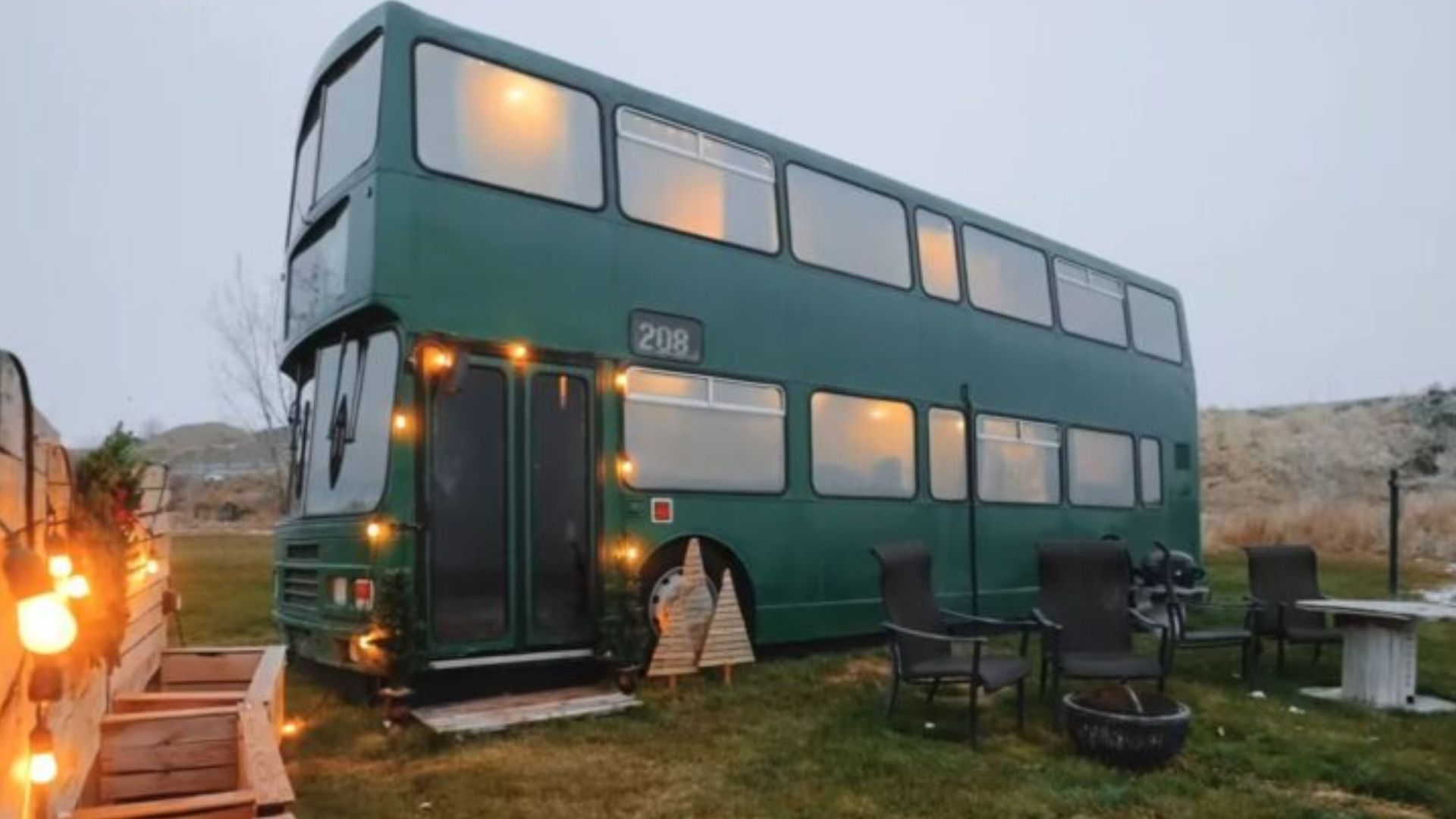 teal blue double-decker bus house with a seating area in the front and lots of string lights