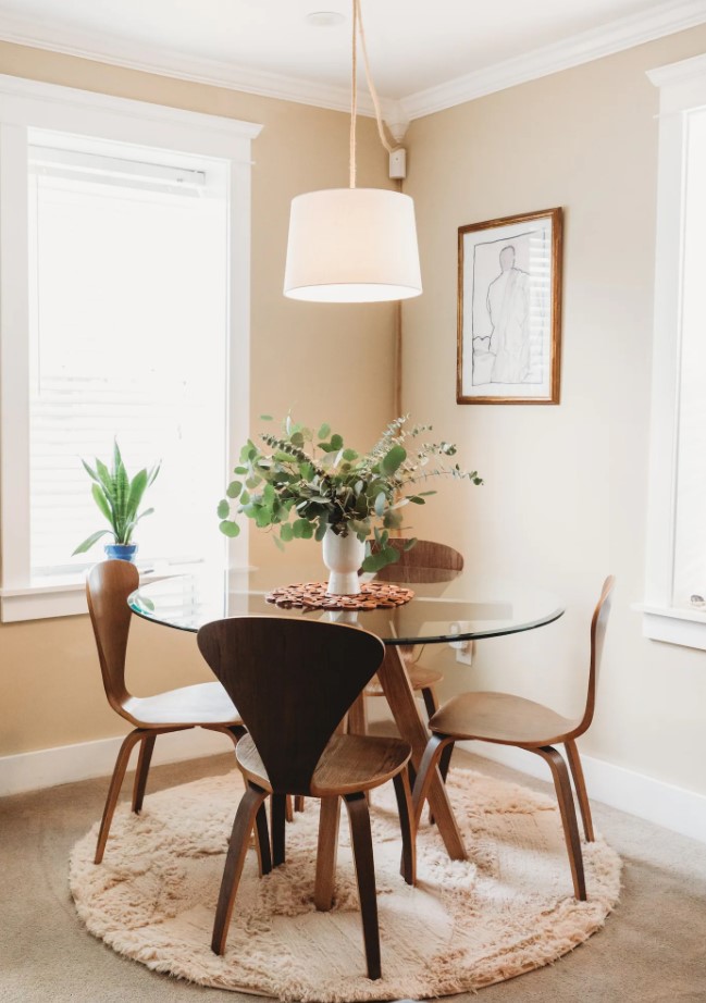 Dining area with glass table, wooden chairs and a light fixture