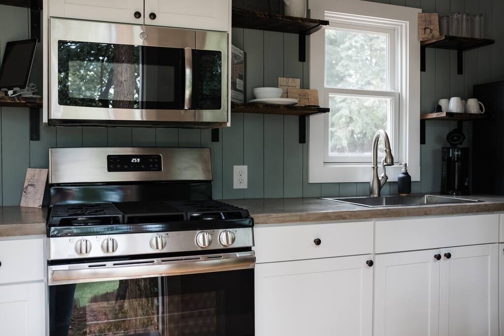 Spacious kitchen in container home with green walls and white cabinets