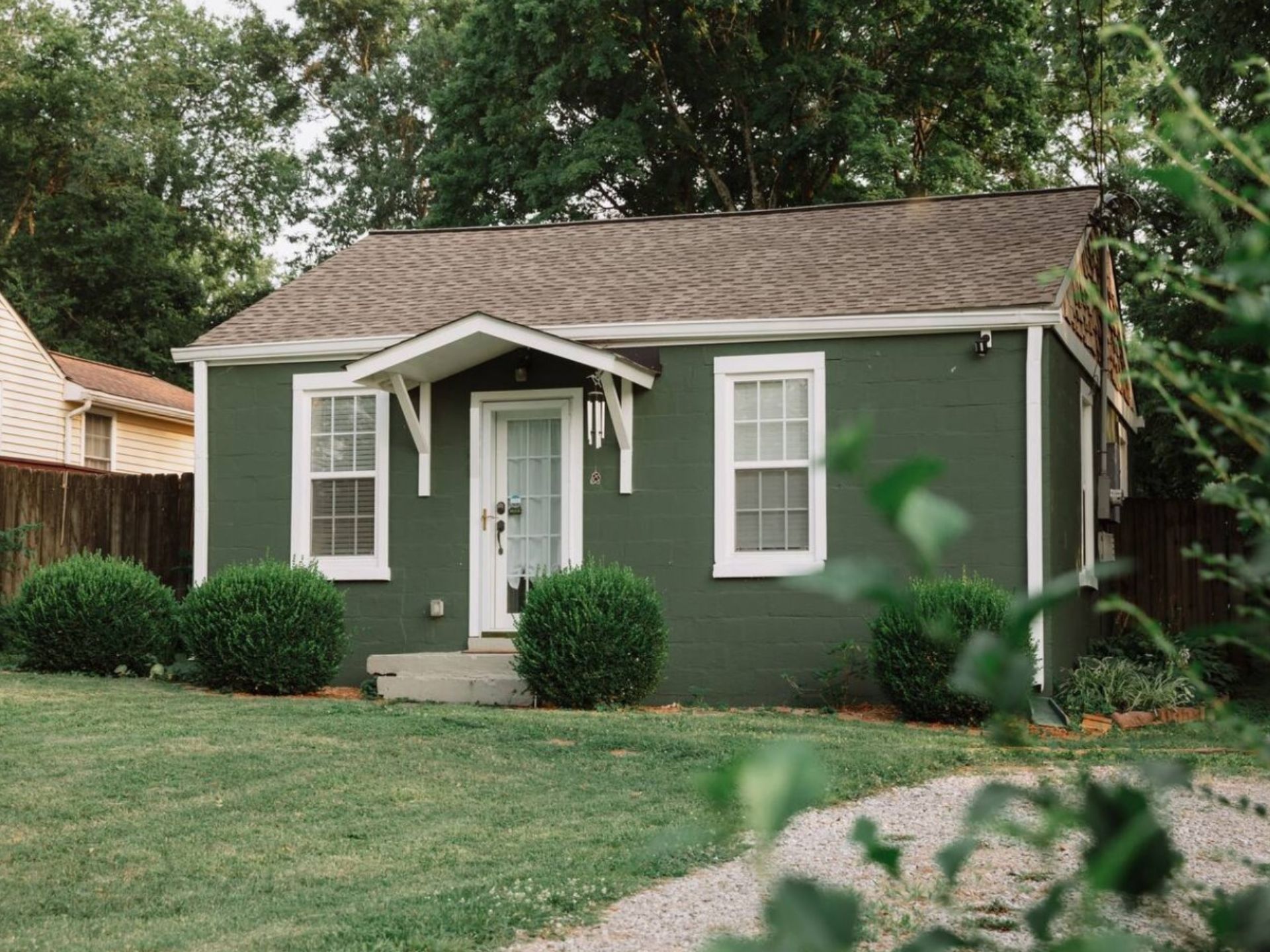 Tiny green home with a front lawn and white windows