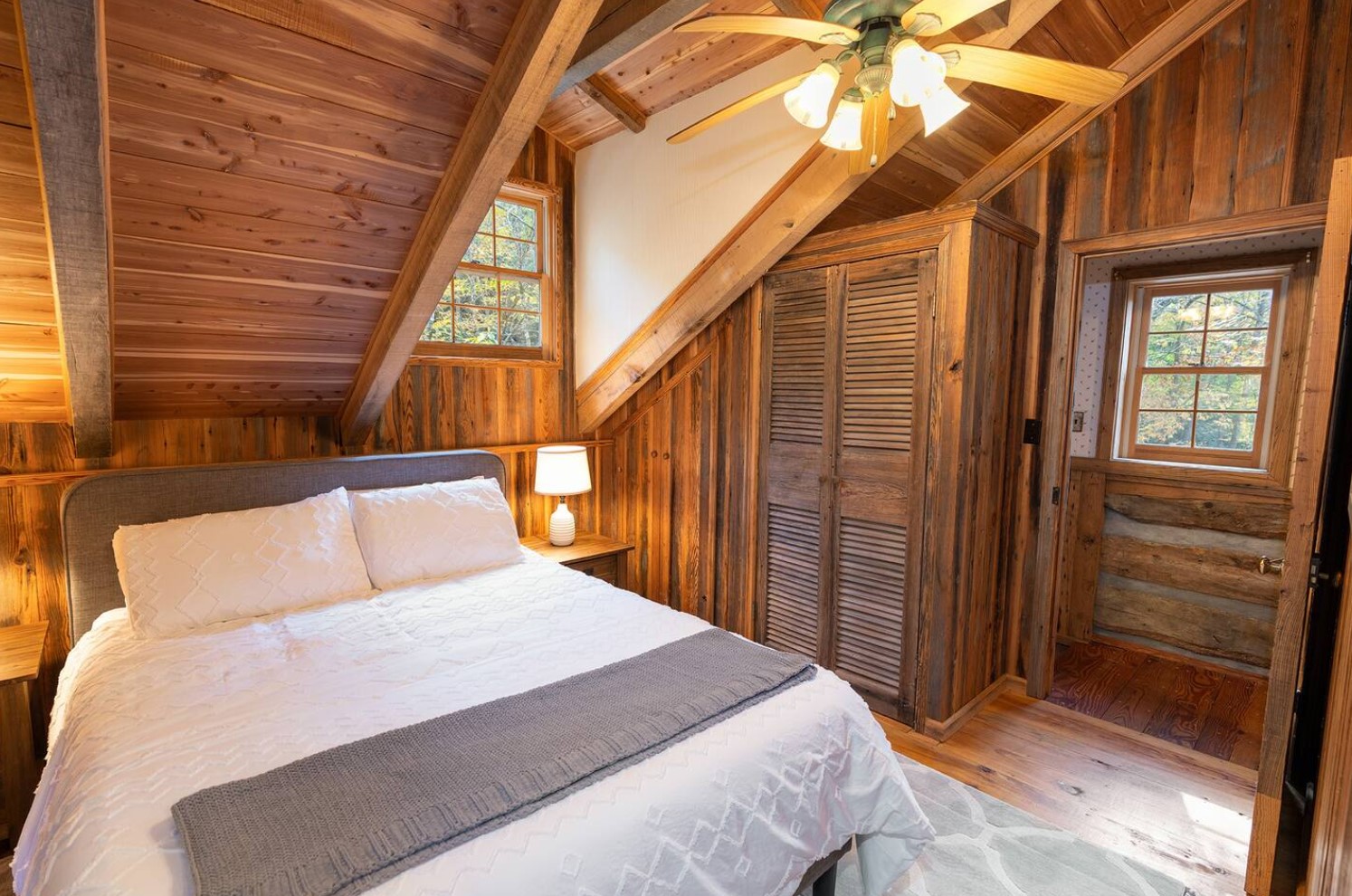 Wooden bedroom with ceiling fan and closet