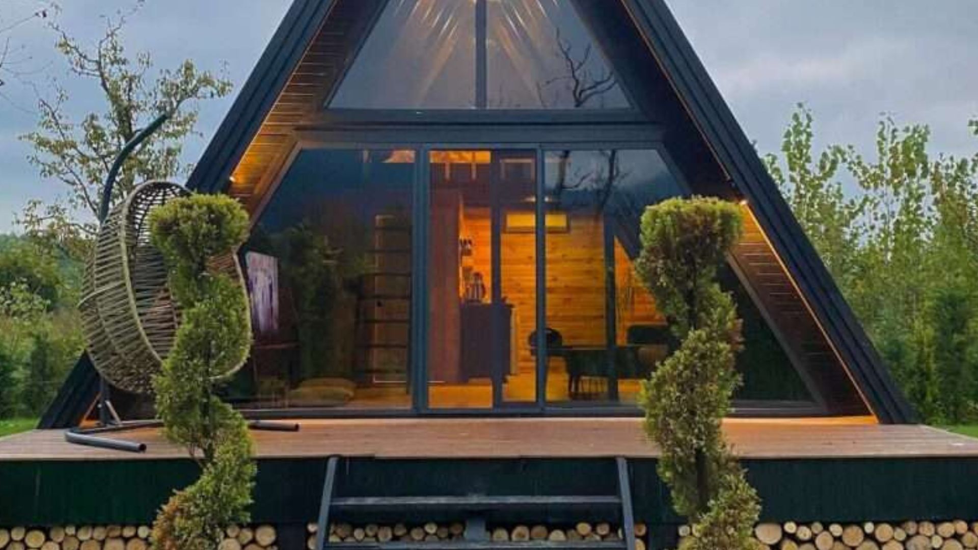 frontal photo of the A-frame bungalow house with two decorative plant by the entrance