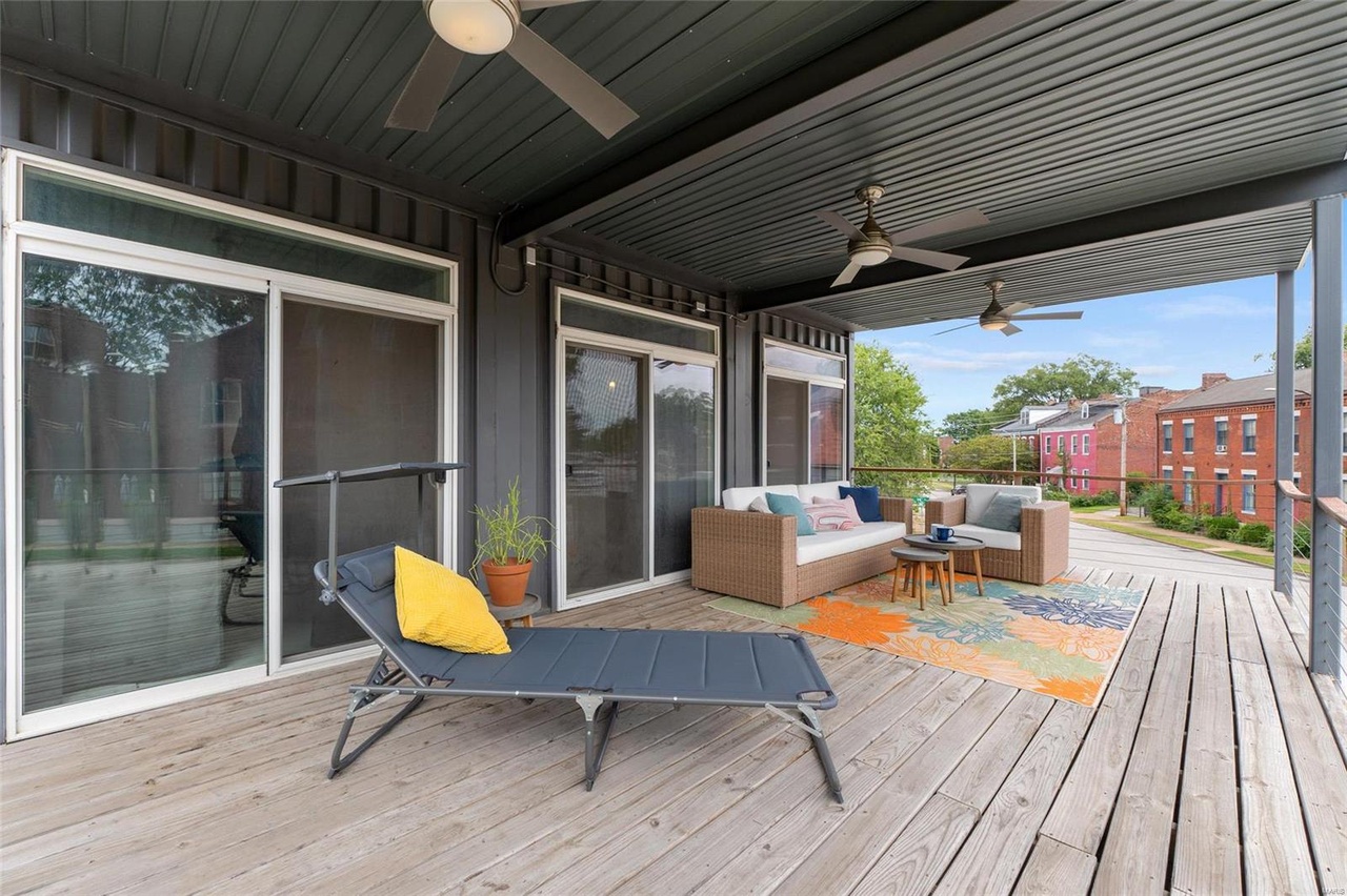 balcony with a white furnished couch, colorful carpet and a deck chair