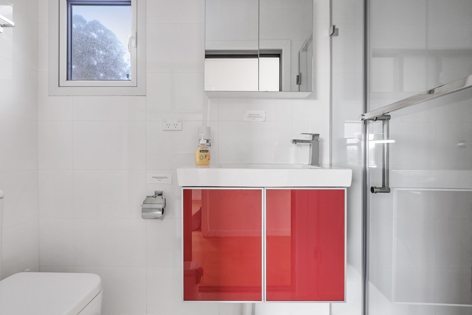 bathroom with a white toilet and white tiles and a red cabinet