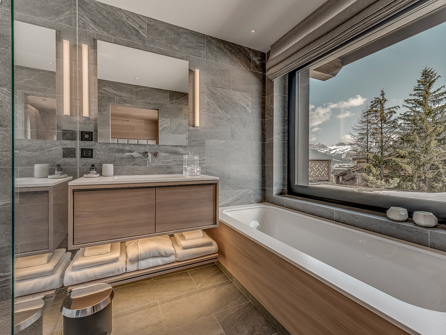 bathroom with a white bathtub, glass shower, big window and blue cabinet