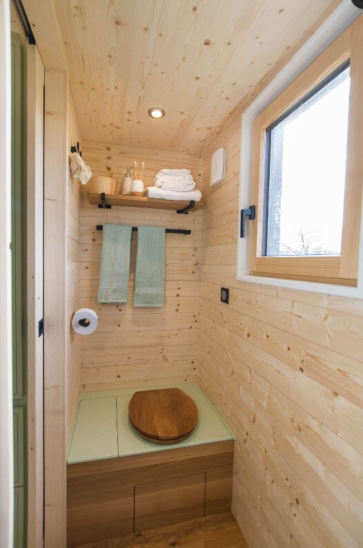 bathroom with brown wooden walls and a window and a unique toilet