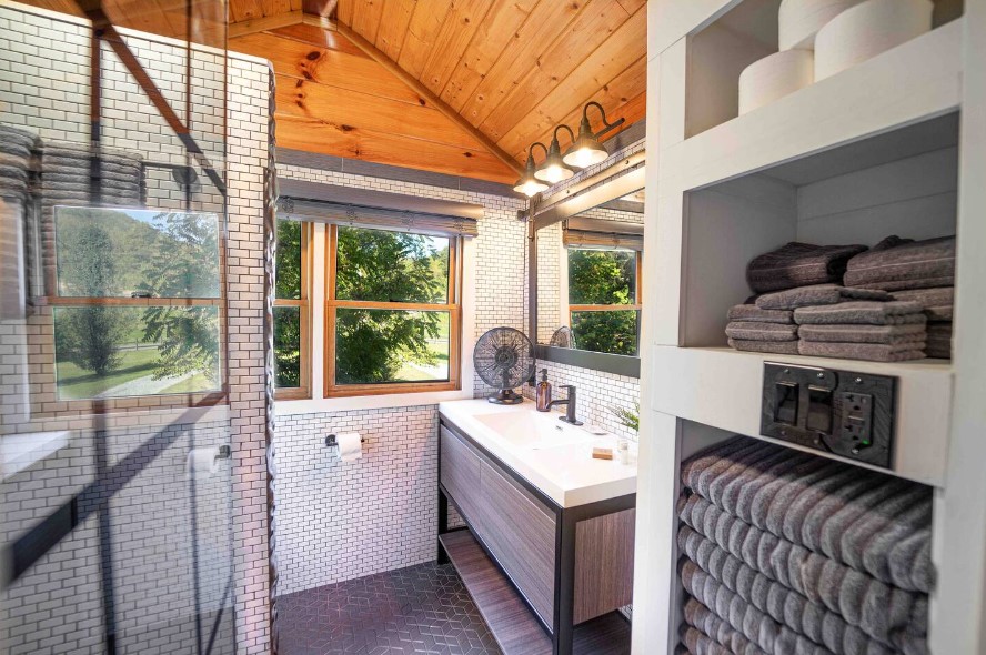 bathroom with white tiles, gray wooden cabinets, glass shower