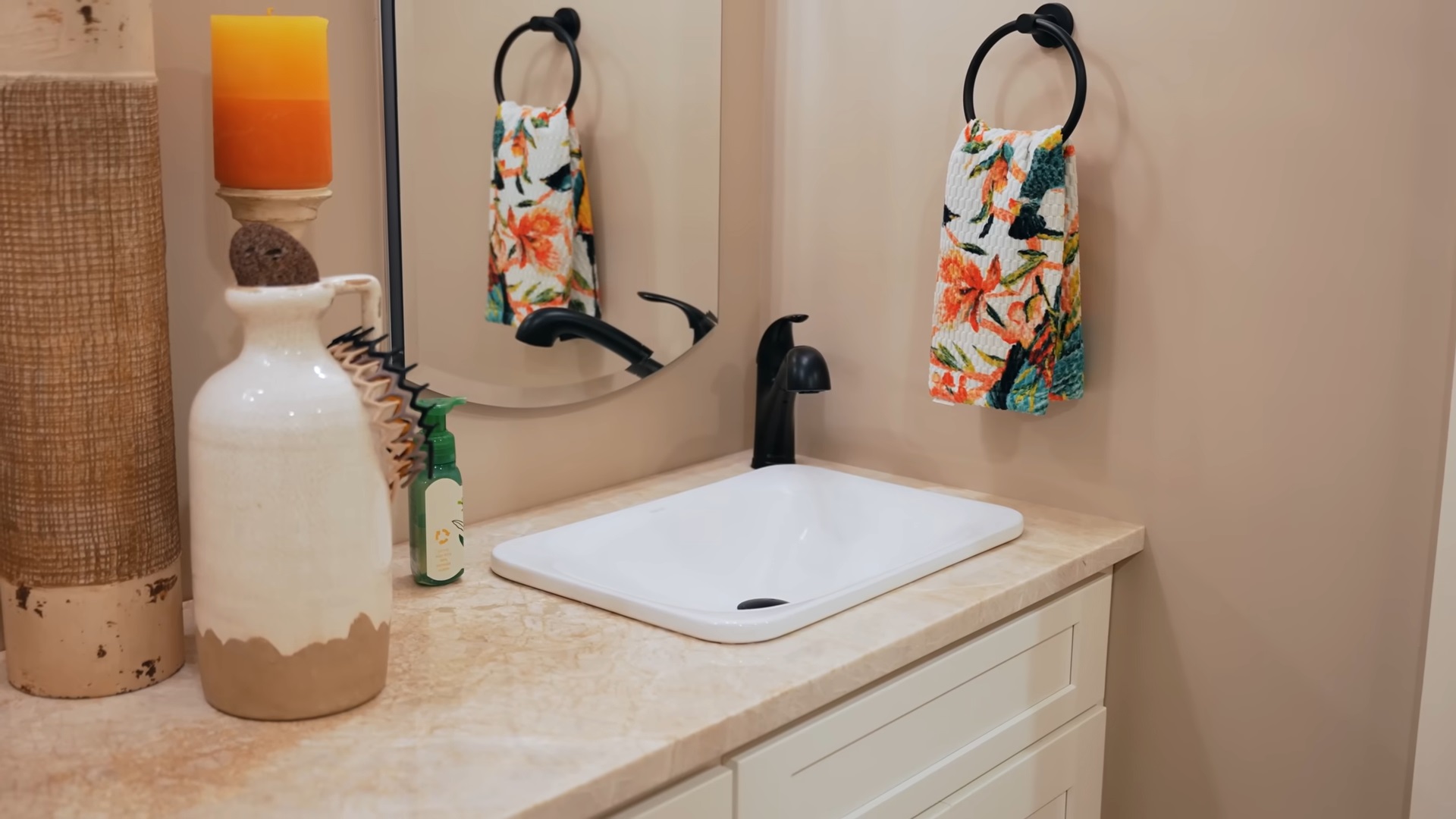 beige cabinet in the bathroom with the white sink and floral towel