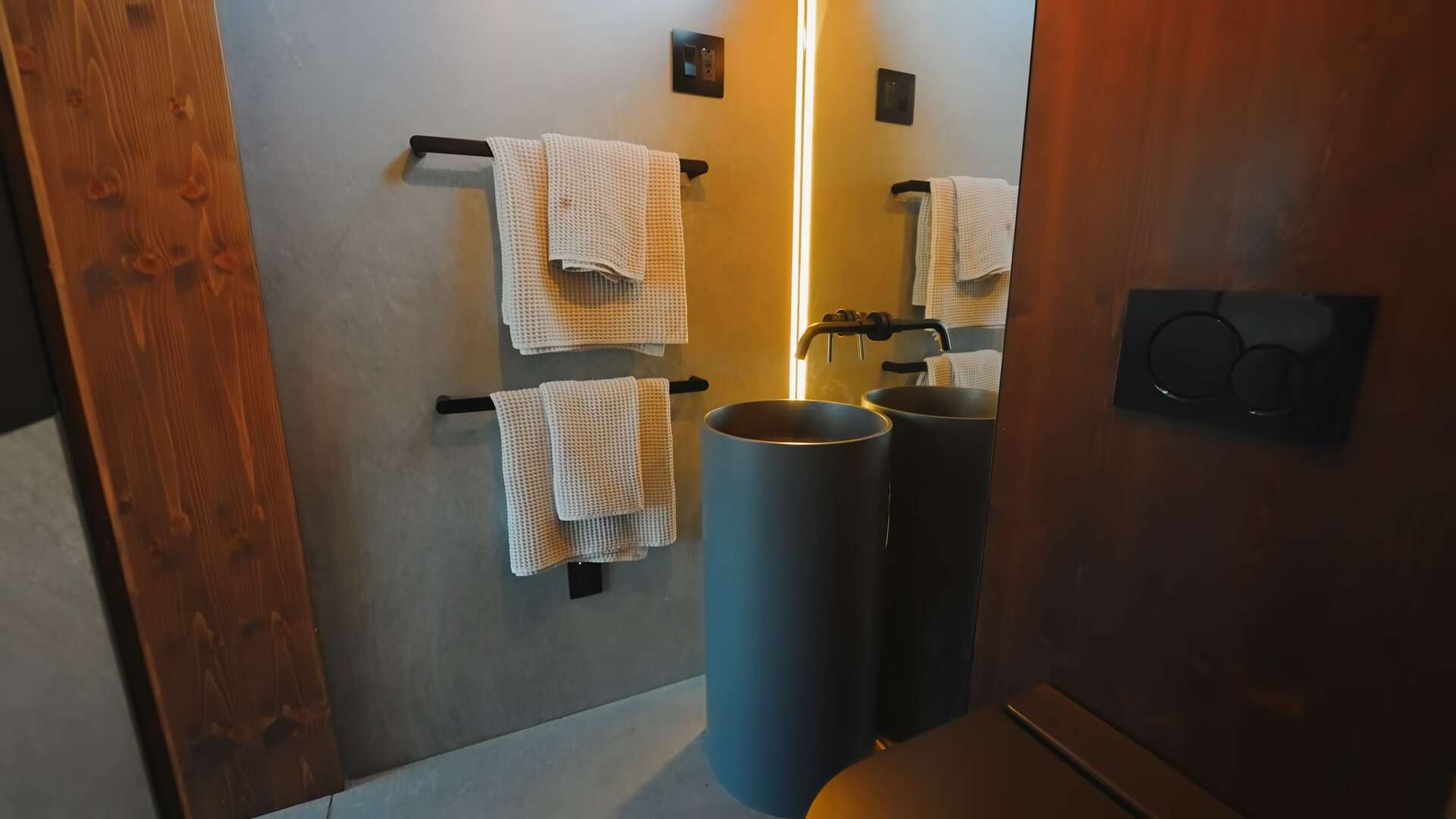 bathroom with a cylindric amenity, big mirror with lights on the side and black toilet