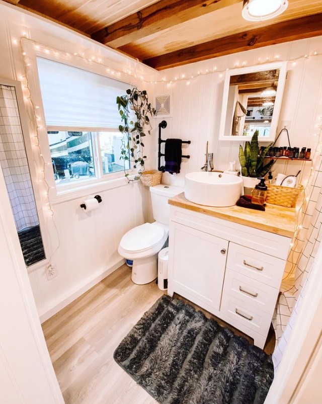 bathroom with a white cabinet, brown countertop, fairy lights