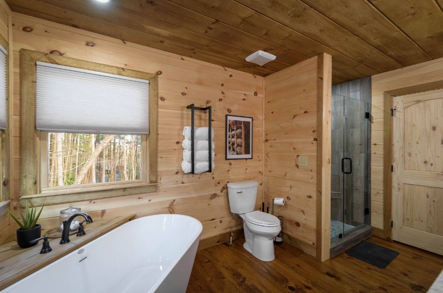 bathroom with a white bathtub, a shower with glass doors, white toilet and a window