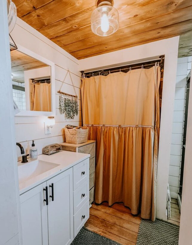 bathroom with an orange shower curtain and a white cabinet