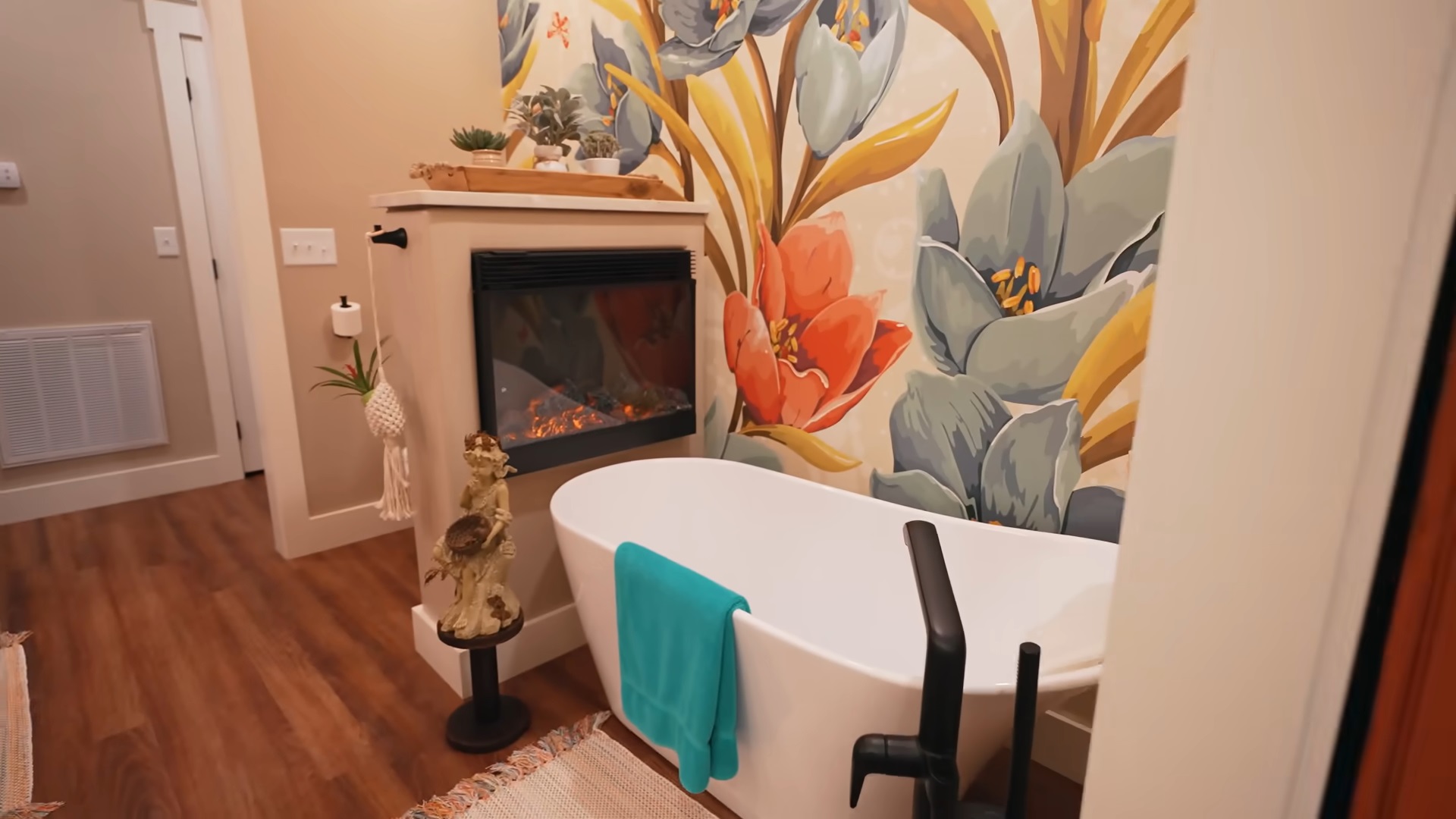 bathroom with a white bathtub and a fireplace and a floral print on one wall