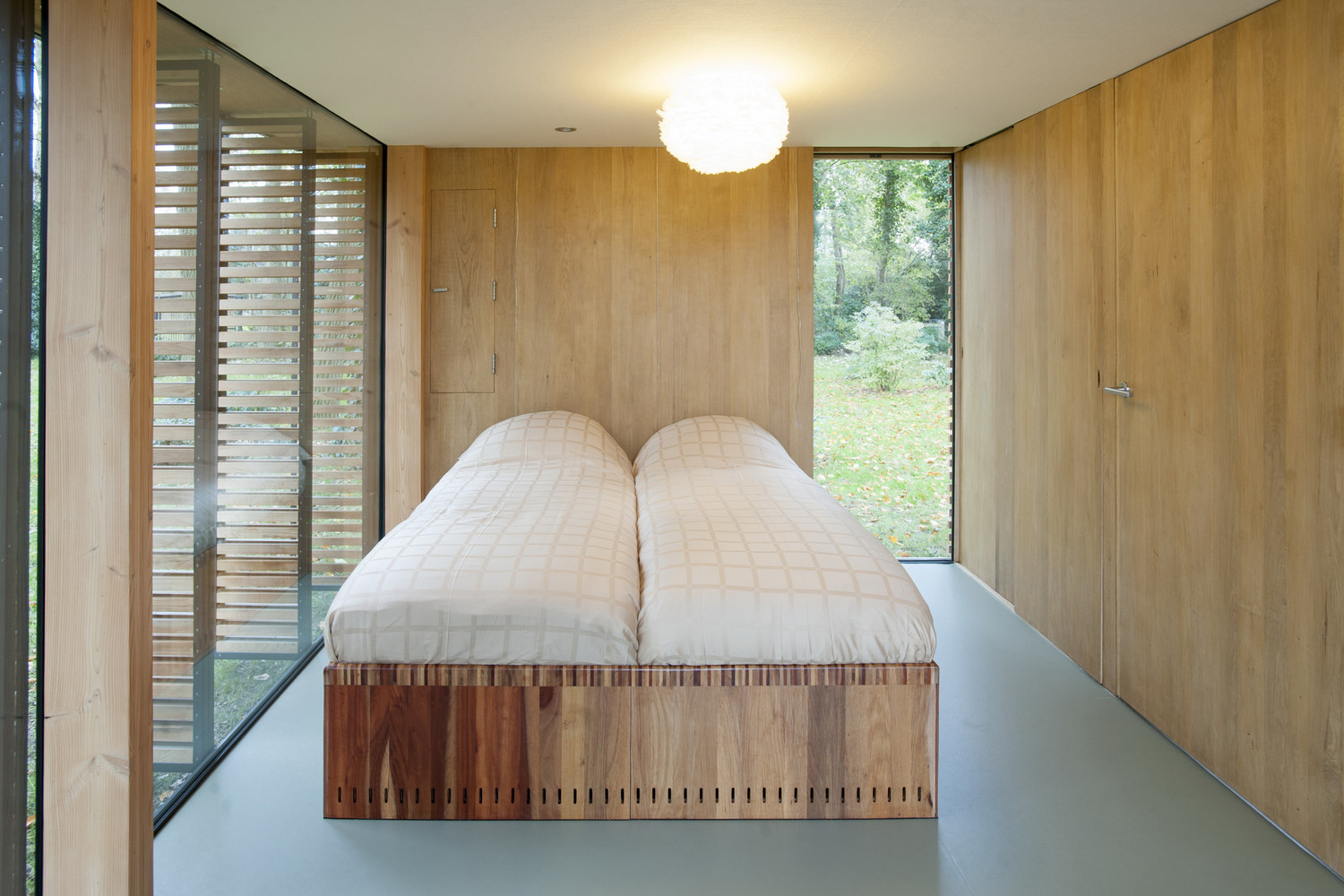 bed in the bedroom of a cabin with a floor to ceiling window