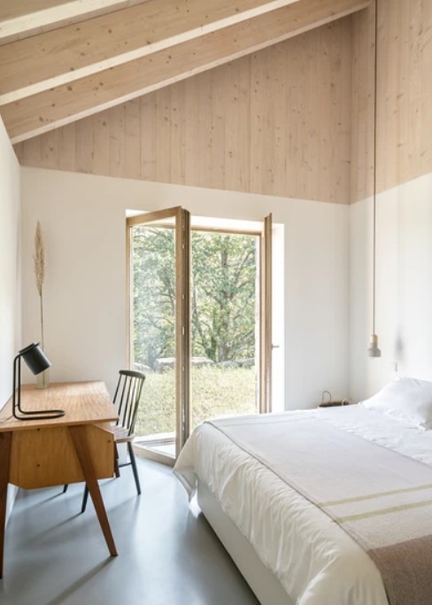 bedroom with a comfy bed and a desk in the corner accompanied by a chair and a lamp on the desk