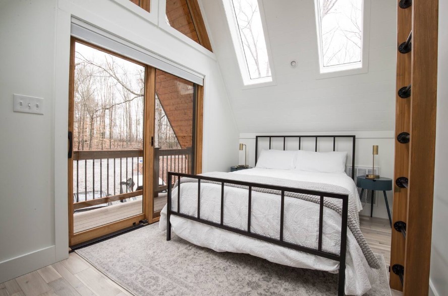 bedroom with a queen-sized bed, balcony, round bedside table and a ladder which lead to the loft