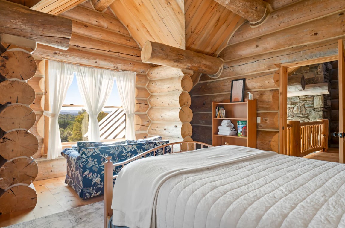 bedroom with a blue floral couch at the end of the bed and the open shelf