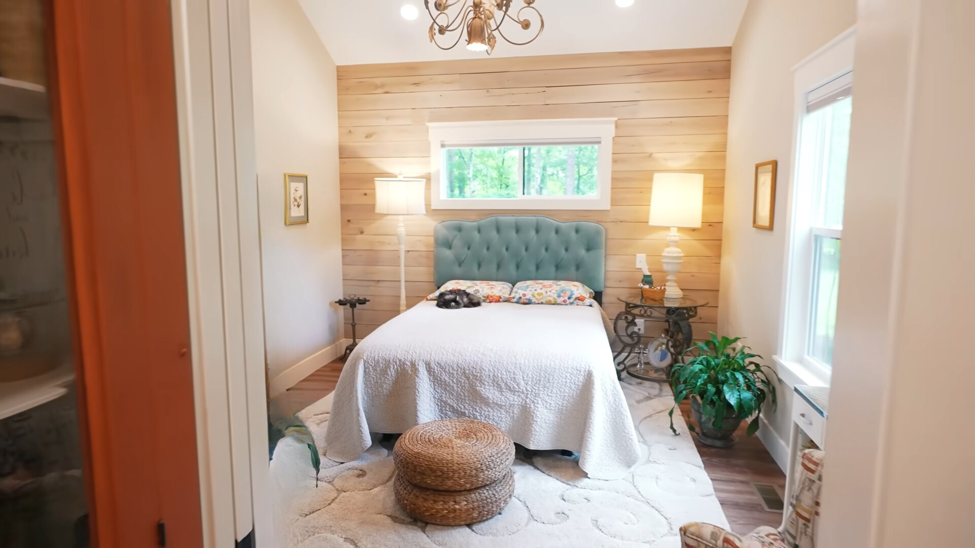 bedroom with a big bed and one wooden wall behind it and two windows