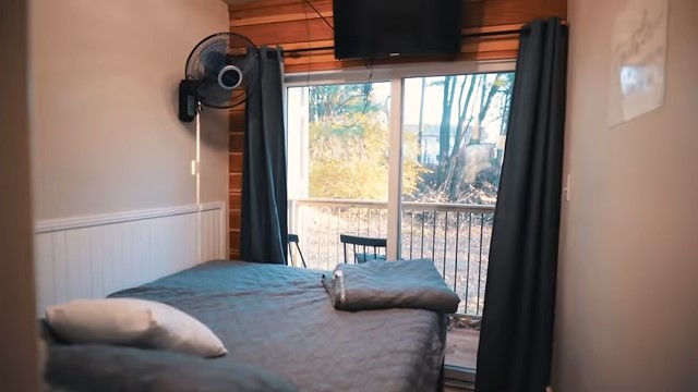 Bedroom with a fan, TV, and a balcony