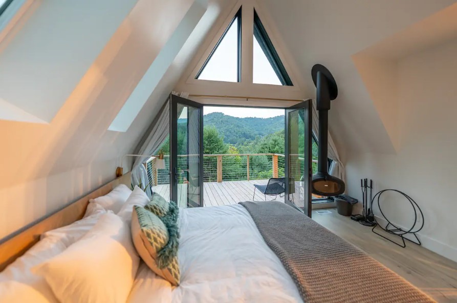 main bedroom with a king sized bed, a hanging fireplace, a private deck