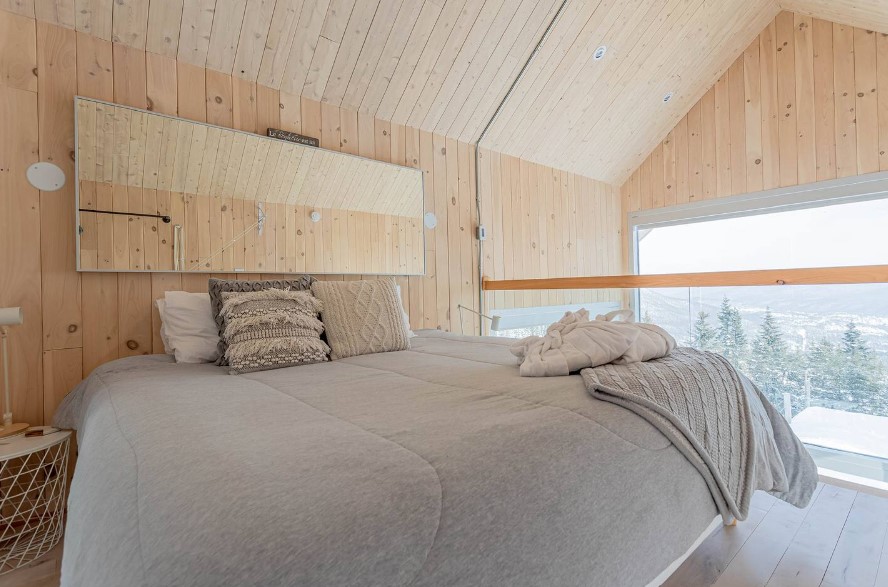 loft bedroom with a view of the entire place, king-sized bed and a mirror above the bed