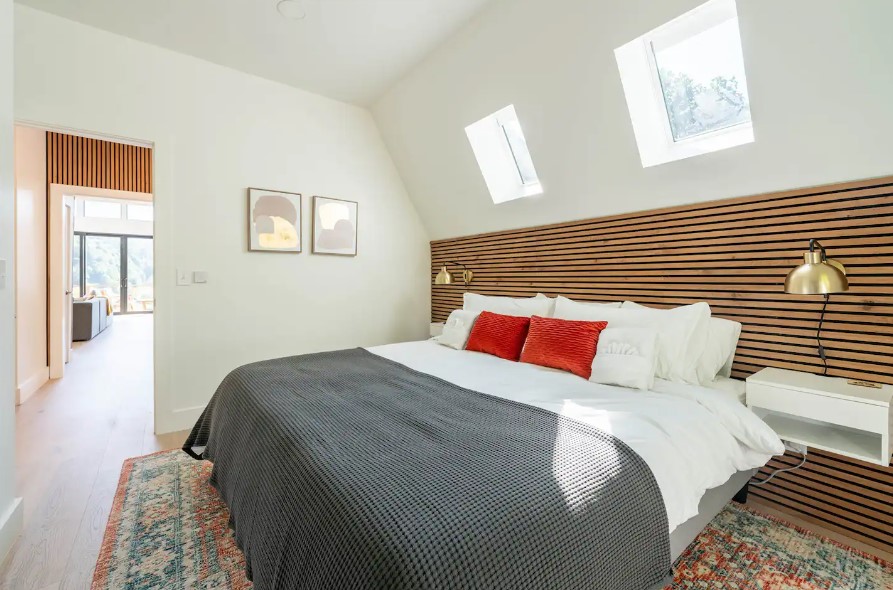 bedroom with a king sized bed and white bedside tables and windows above the bed