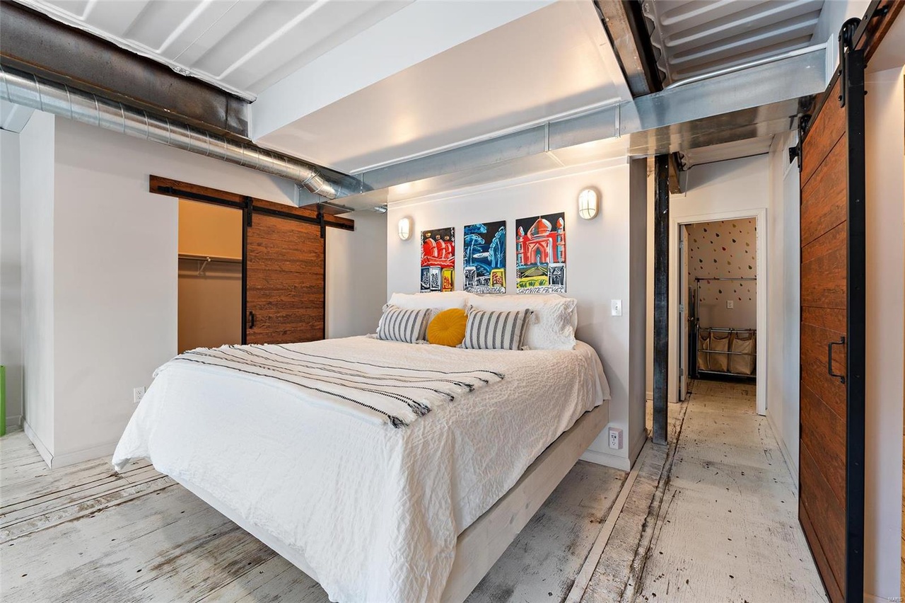 bedroom with three artworks above the bed and a brown closet