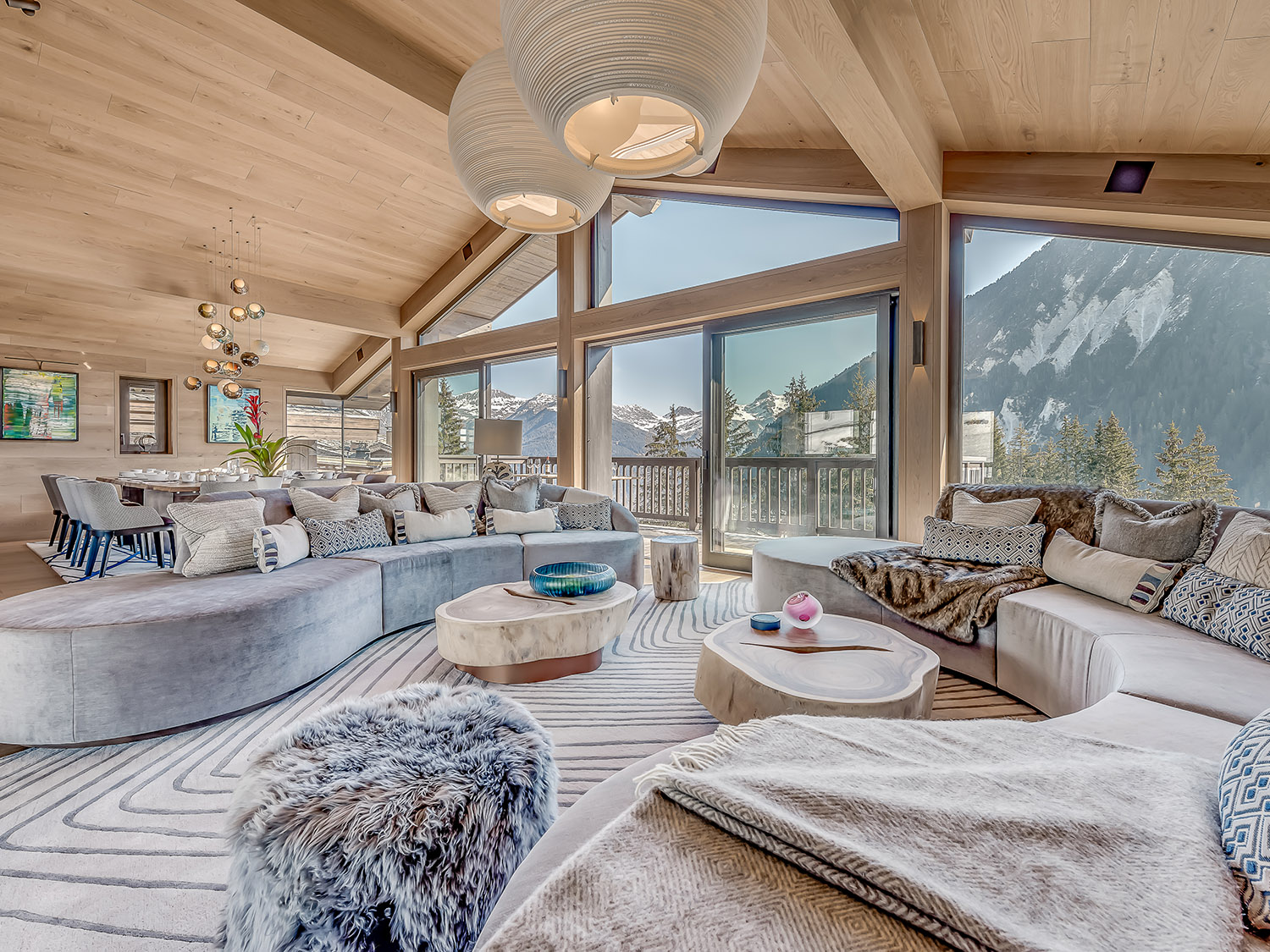 living room of a cabin with floor to ceiling windows, two large couches and two tiny wooden tables