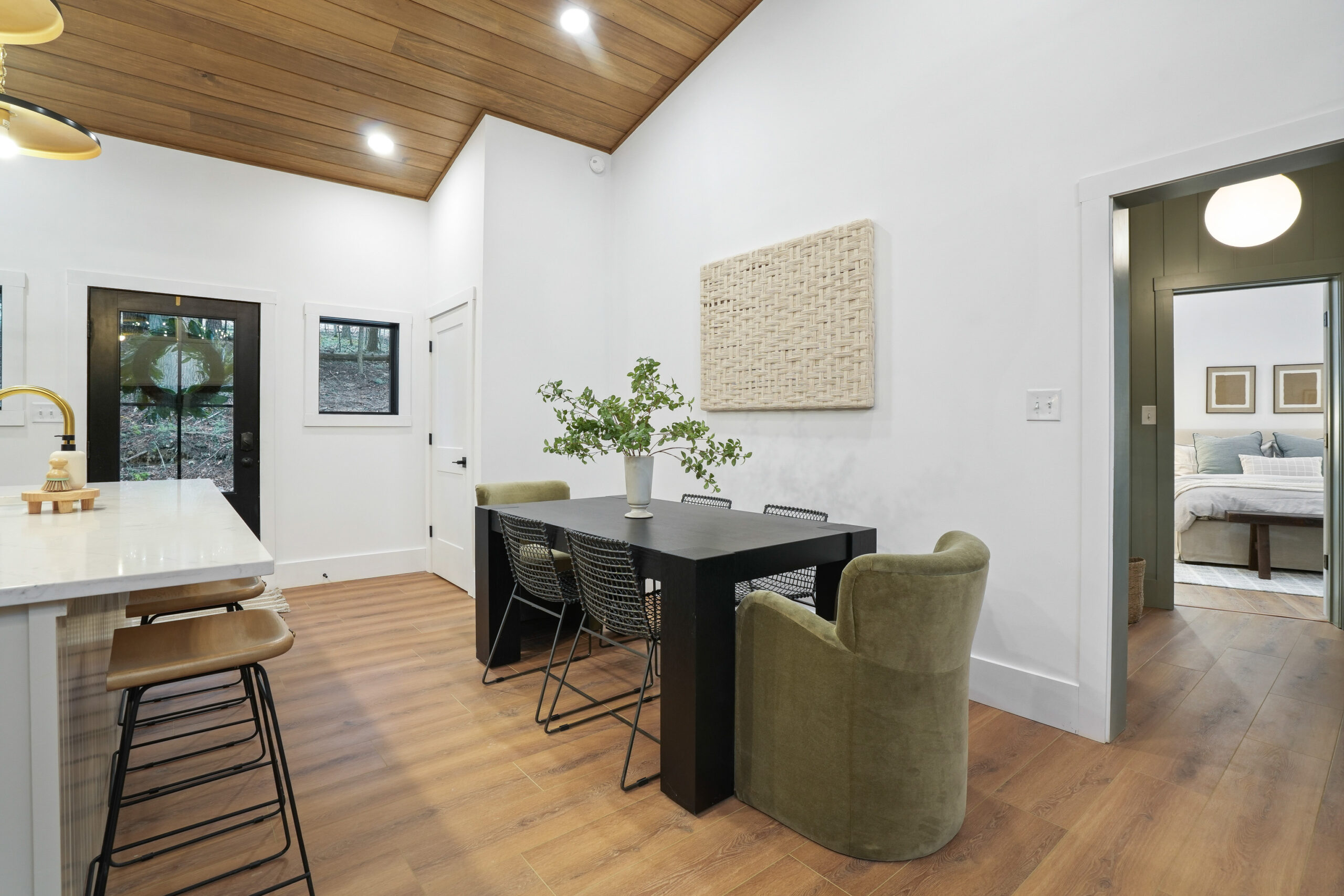 black dining table with black chairs and two green chairs