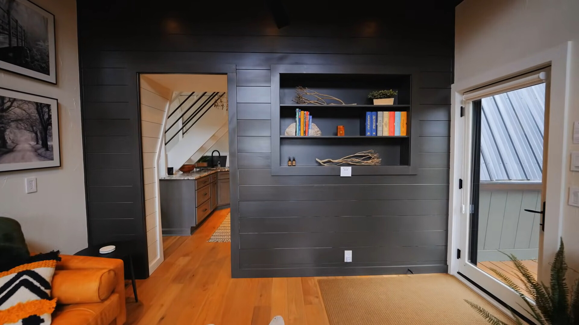 black wall of the living room with a built in shelf filled with books and other decorations