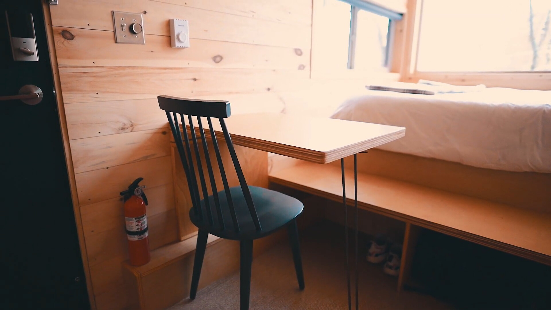 brown desk and a black chair next to the bed