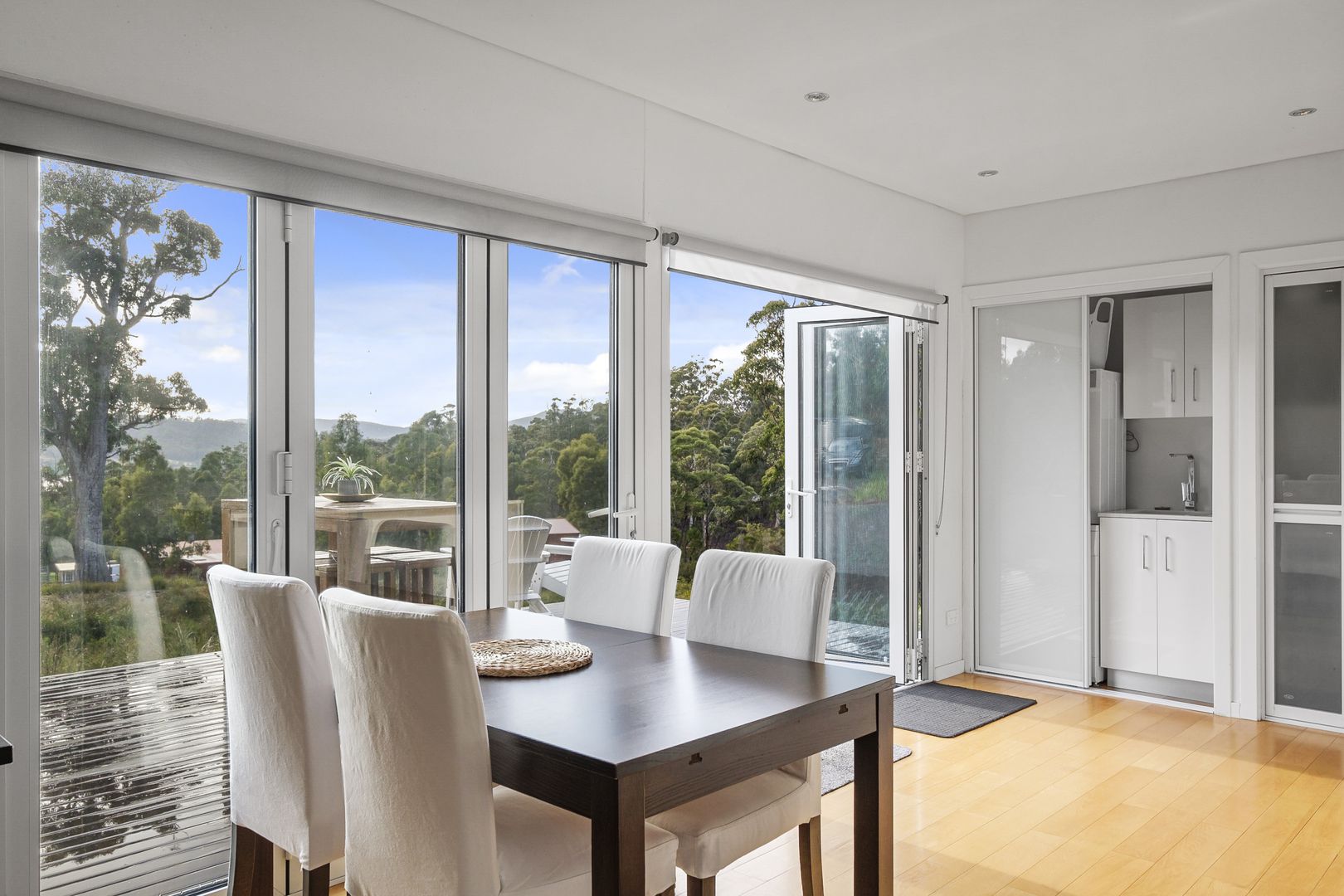 brown dining table and white chairs and glass doors