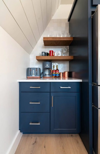 small coffee area in the kitchen with a blue cabinet and a white countertop and floating brown shelves