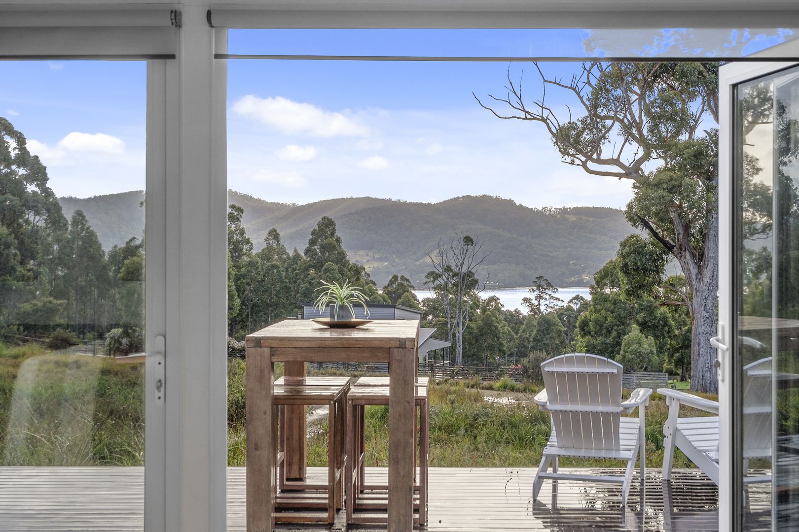 deck with white chairs, brown table and four brown bar stools