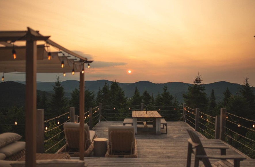 dining table and benches and deck chairs on the terrace of a cabin in the mountains