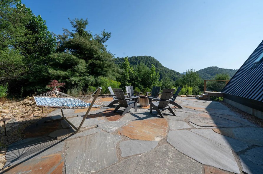 fire pit with chairs around it and a hammock on the outside of the house