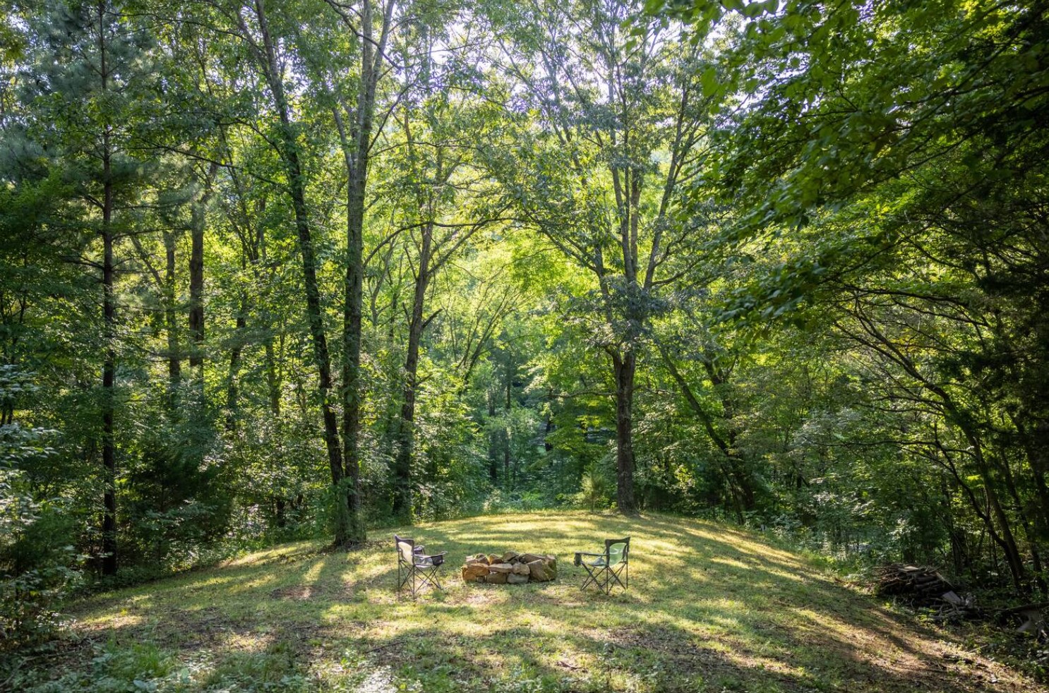 A fire pit hidden in the woods with two chairs